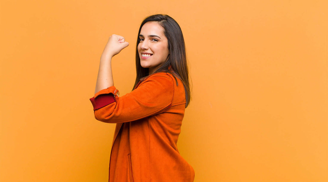 Fist-raising young woman promotes immunity boosters on orange background