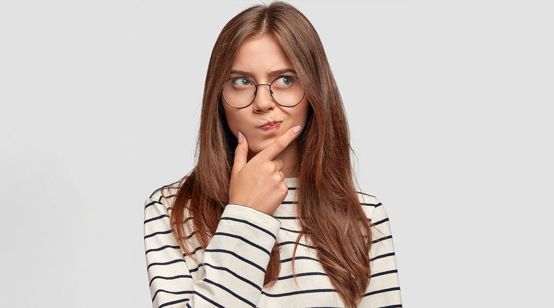 An inquisitive woman donning glasses, her face adorned with a question mark, pondering the advantages of Elderberry Gummies for maintaining good health