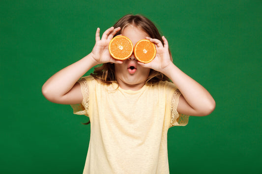 Young girl hiding her eyes behind orange